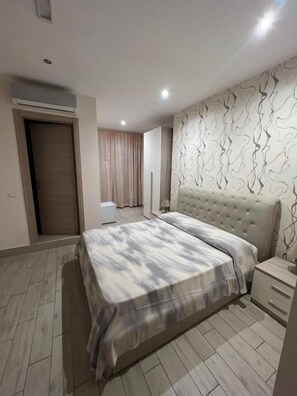 A bedroom with a bed, bedside table, and a wardrobe. - La Suite (Cassino)