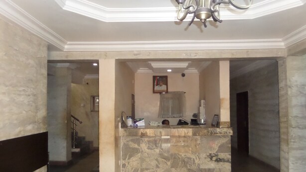 A lobby with a marble reception desk, a staircase, and a chandelier. - Chinox Guest Inn (Abuja)