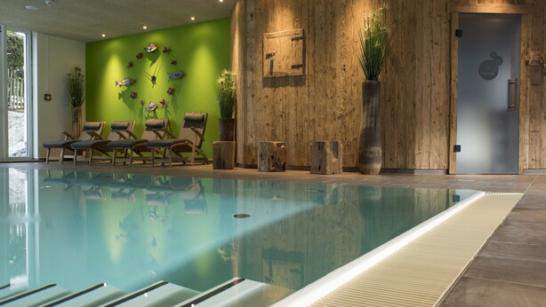 Une piscine avec des chaises longues et un mur en bois doté d’une porte.