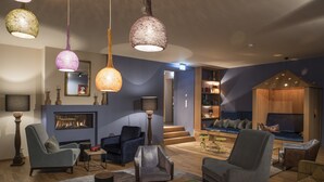 Un salon moderne doté d’une cheminée, de sièges confortables et d’un éclairage décoratif.