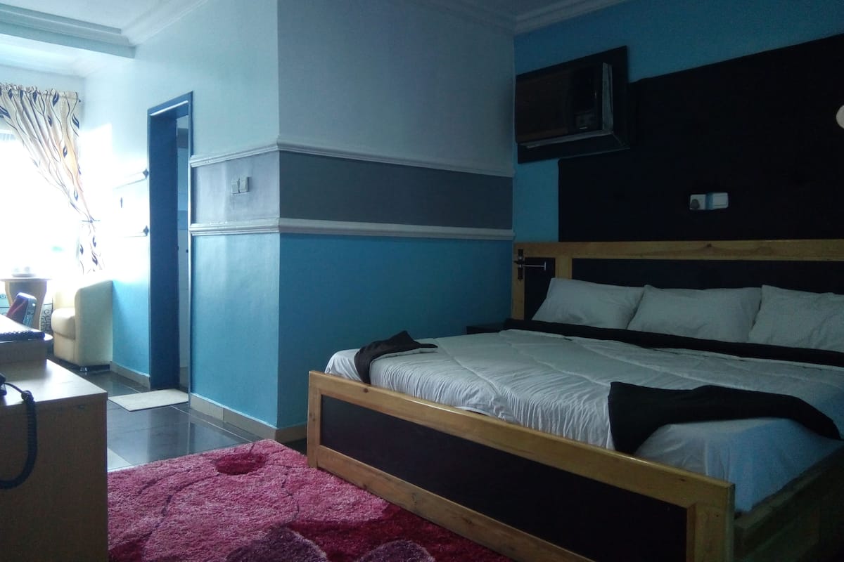 A bedroom with a bed, a television mounted on the wall, and a desk with a chair.