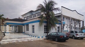 Un edificio con entrada de baldosas, una palmera y automóviles estacionados.