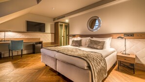 A bedroom with a bed, bedside table, and a desk with a chair. - Hotel Vilnia (Vilnius)