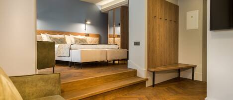 Un dormitorio moderno con una cama grande, un armario de madera y una zona de estar con sofá y sillón.