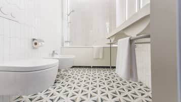 A modern bathroom with a geometric tile floor, a toilet, a sink, and a shower area.