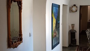 Un pasillo con suelo de mármol, un espejo grande y un cuadro en la pared.