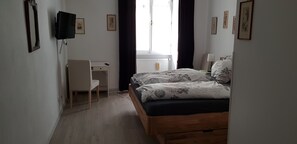 Une chambre à coucher avec un lit, un bureau, une chaise et un téléviseur.
