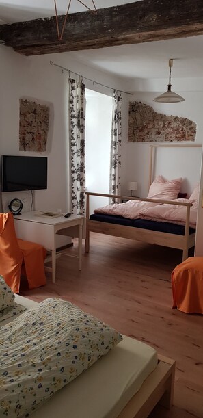 Une chambre à coucher avec un lit en bois, un bureau avec une chaise, une télévision et une fenêtre avec des rideaux.