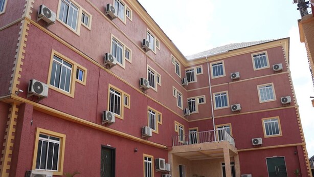 Un edificio de varios pisos con fachada roja, numerosas ventanas y unidades de aire acondicionado.