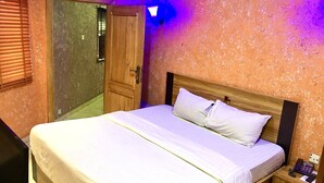 Een slaapkamer met een houten bed, witte beddengoed, een nachtkastje met een telefoon en een deur naar een balkon.