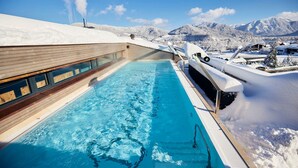 Un espace piscine doté d’une terrasse en bois et offrant une vue sur des montagnes enneigées.