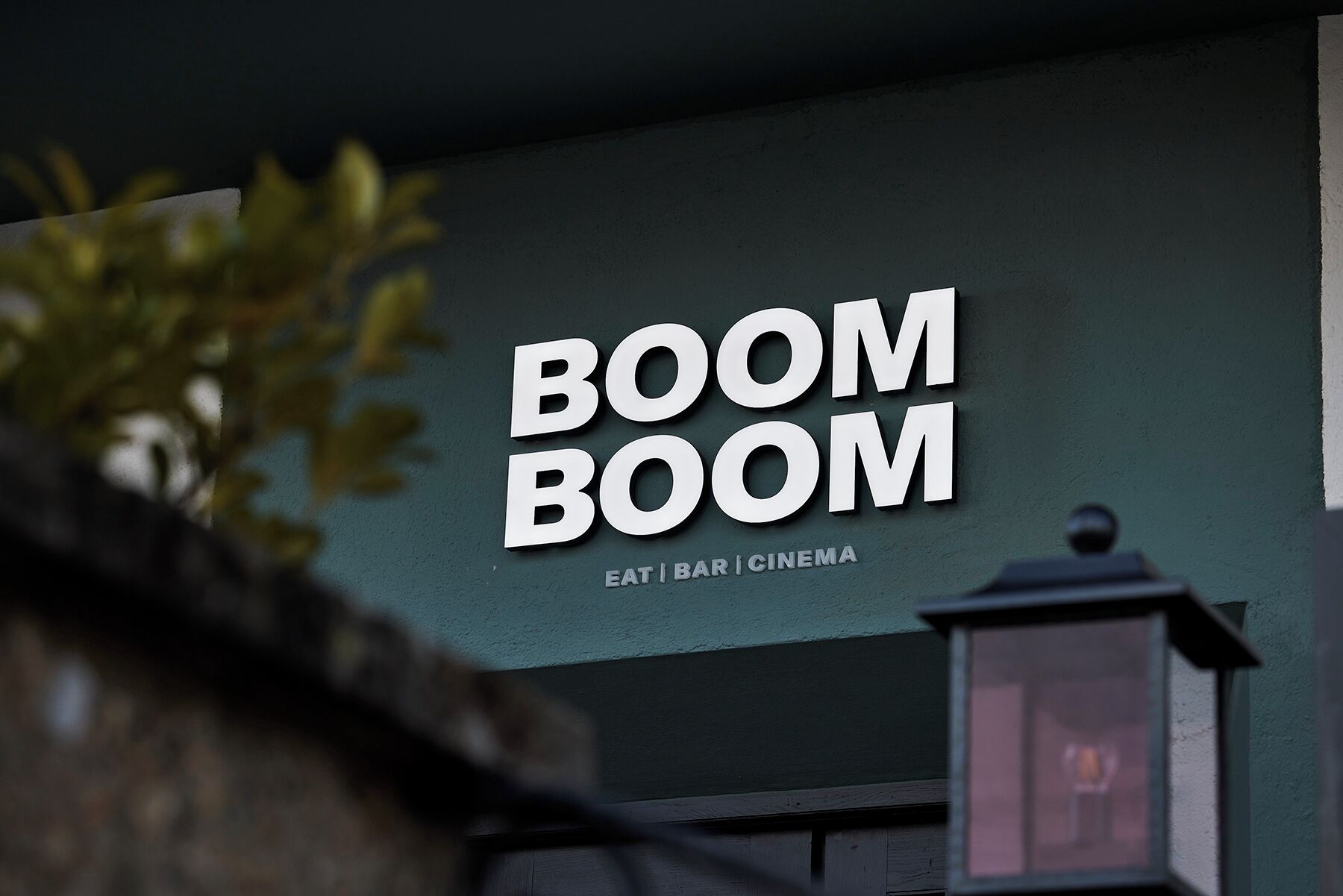Un edificio con un cartel que dice 'BOOM BOOM' y debajo menciona 'COMER | BAR | CINE'.