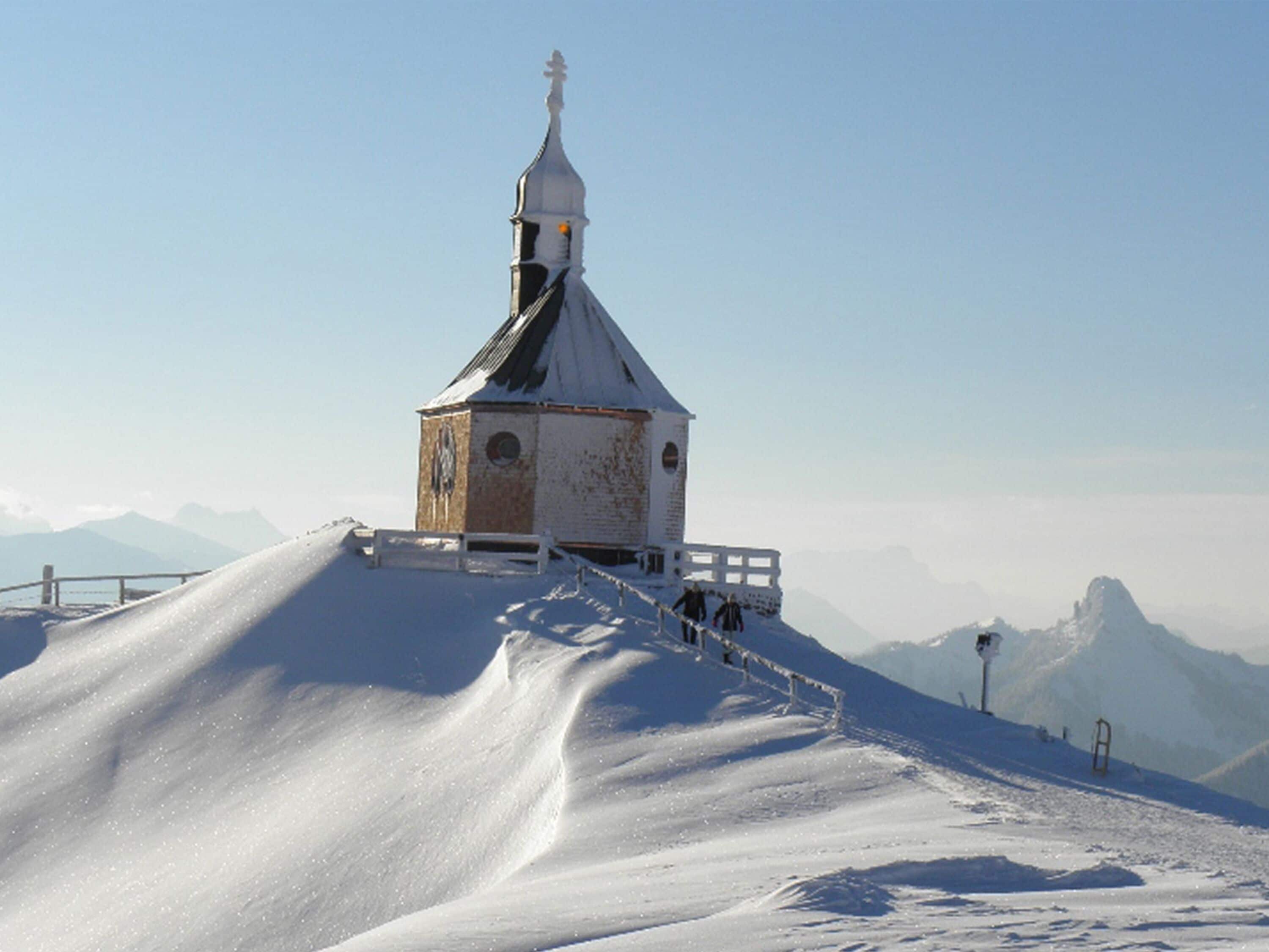 A snow-covered church with a bell tower on a hill.