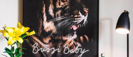 A framed poster of a tiger with the text "ROAR MORE" and "Busi Baby" on a wall.