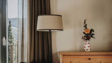 Una habitación con sofá, cómoda de madera, lámpara y un jarrón con flores.