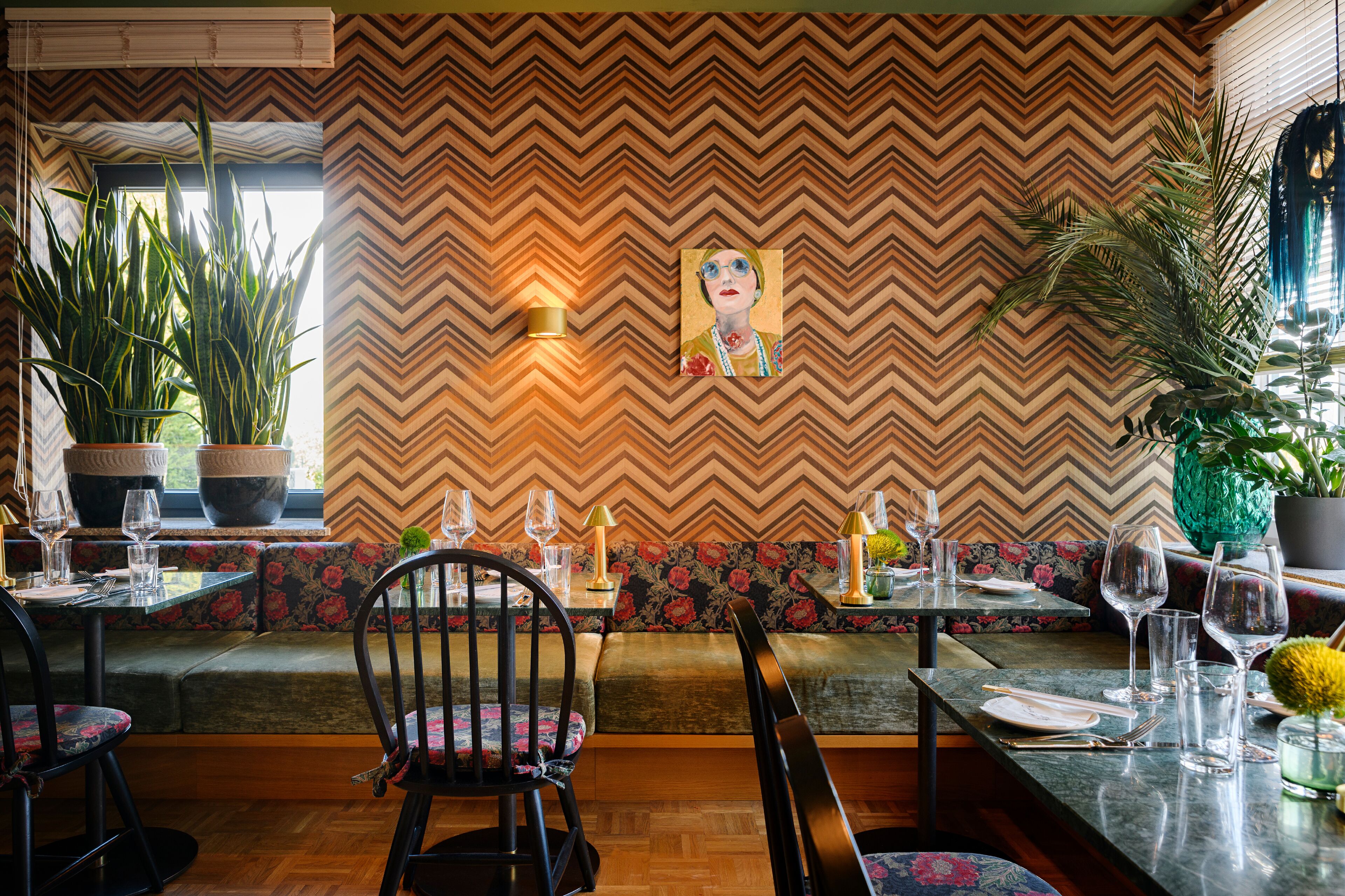 A dining area with a chevron-patterned wall, a painting, and potted plants.