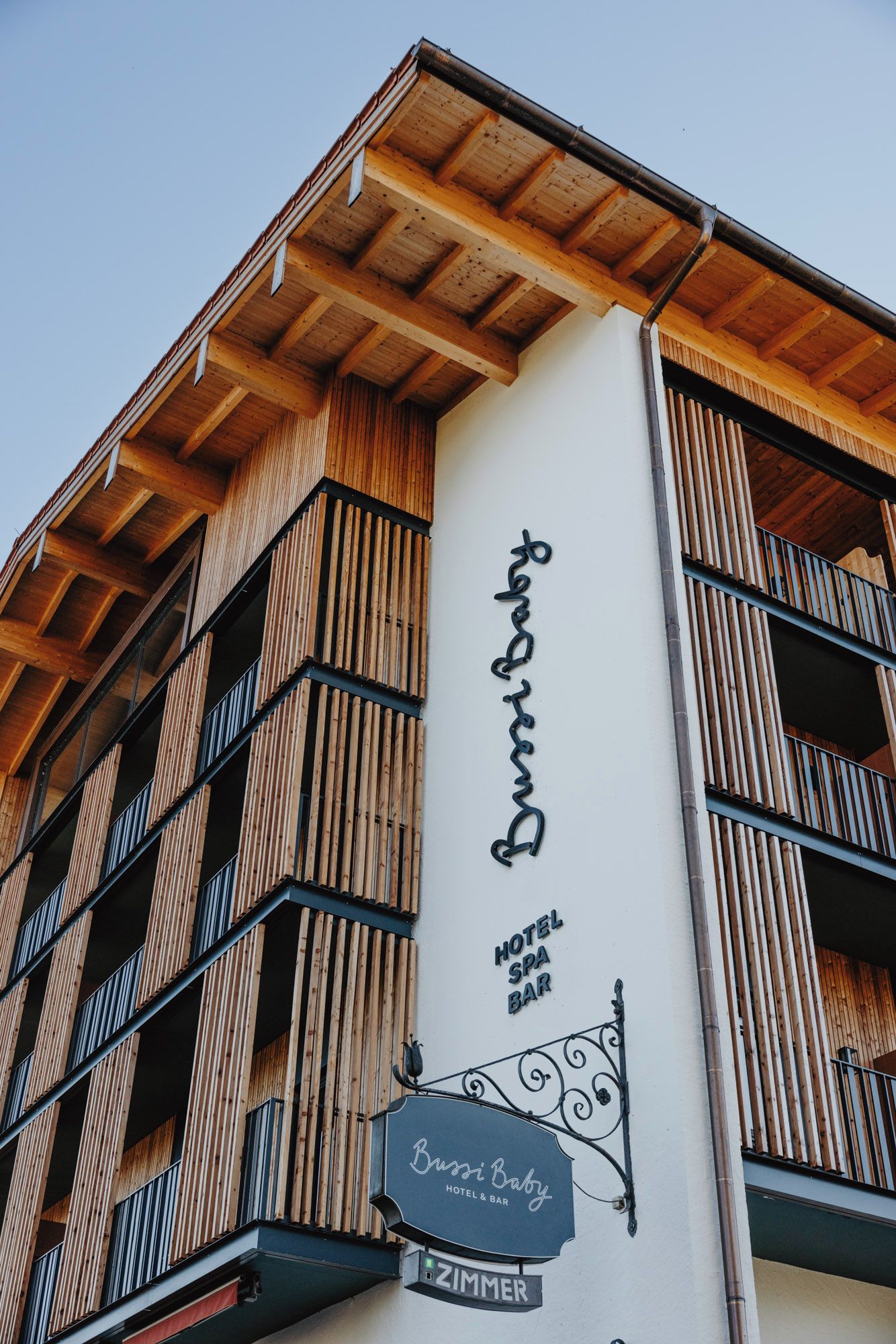 A building with a wooden facade and a sign for 'Bussi Baby Hotel & Bar'.