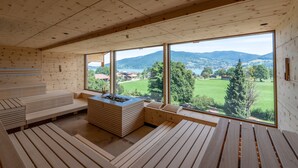 Une cabane en bois dotée de grandes fenêtres qui offrent une vue sur un paysage verdoyant et des montagnes.