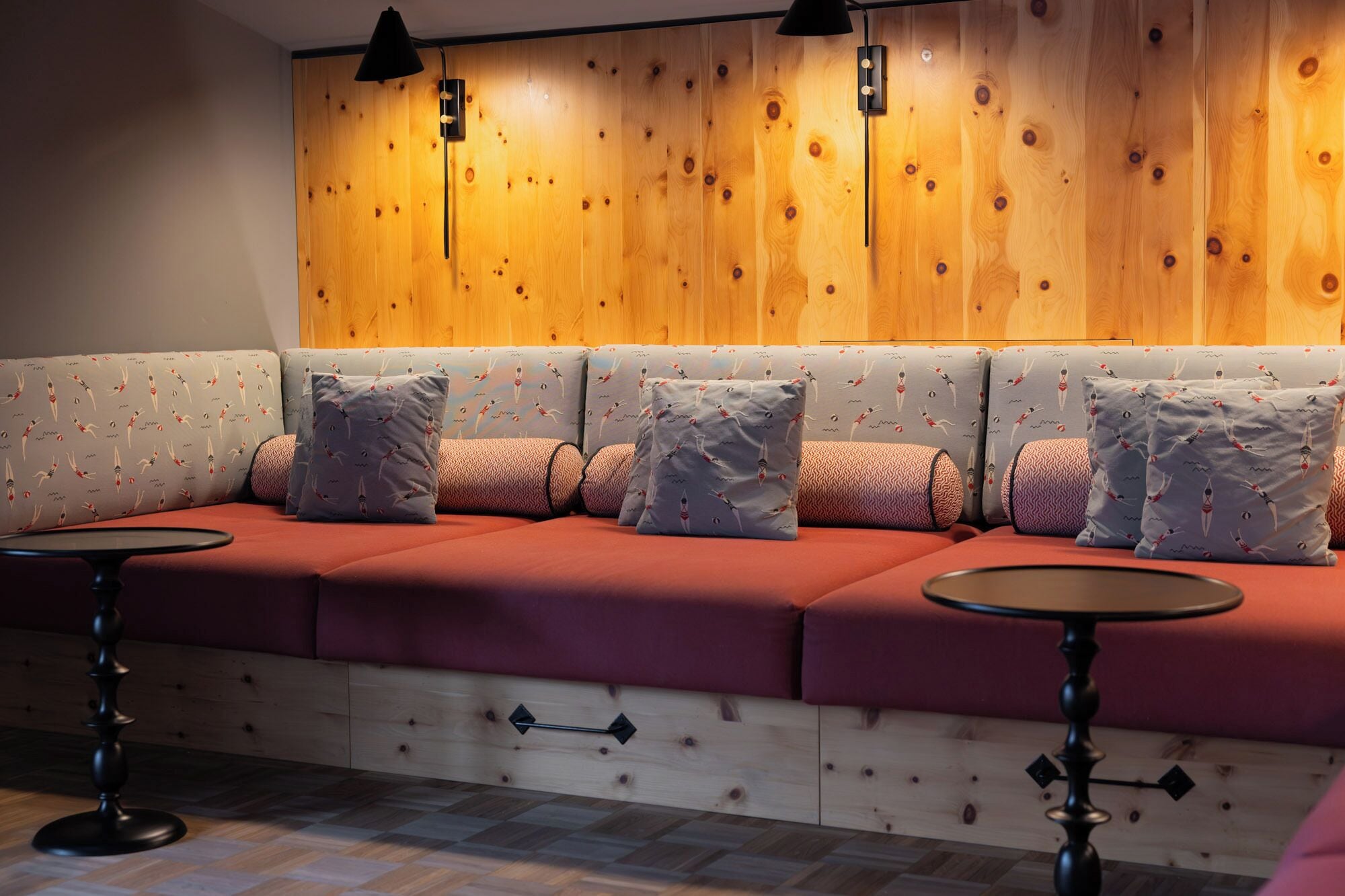 Una zona salotto con parete in legno, panche imbottite e due tavolini rotondi.