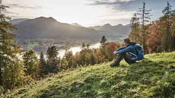 A person sitting on a grassy hill overlooking a lake and mountains.