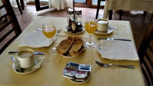 Taula de dinar posta amb una tassa de cafè, un got de suc d'aranja, un plat de pa, un got de vi i un pot petit de mantega.