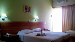 Habitación de hotel con cama doble, lámparas de noche, teléfono en la mesita, una pequeña mesa con una bandeja de objetos y un cuadro en la pared.