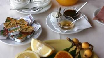 A breakfast setting with a variety of foods including bread, fruit, and beverages on a table.