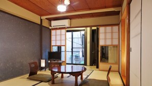 Una habitación japonesa tradicional con suelo de tatami, una mesa baja, cojines y puertas correderas.