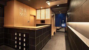 A hotel reception area with a reception desk, a blue directional sign, and a wall-mounted air conditioning unit. - Kyoto Sanjo Ohashi (Kyoto)