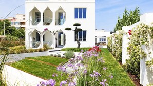 Un bâtiment moderne de couleur blanche, doté d’un jardin bien entretenu et surplombant un ciel dégagé.