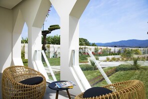 A balcony with wicker chairs and a table, overlooking a landscaped garden and mountains. - Villa Vi (Quartu Sant'Elena)