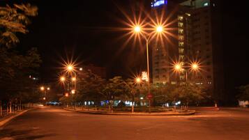 A nighttime street scene with streetlights and a building with illuminated windows.
