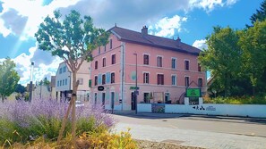 A pink building with a sign for Hotel Jurjura, a bar, and a historical center. - Hôtel JurJura (Dole)