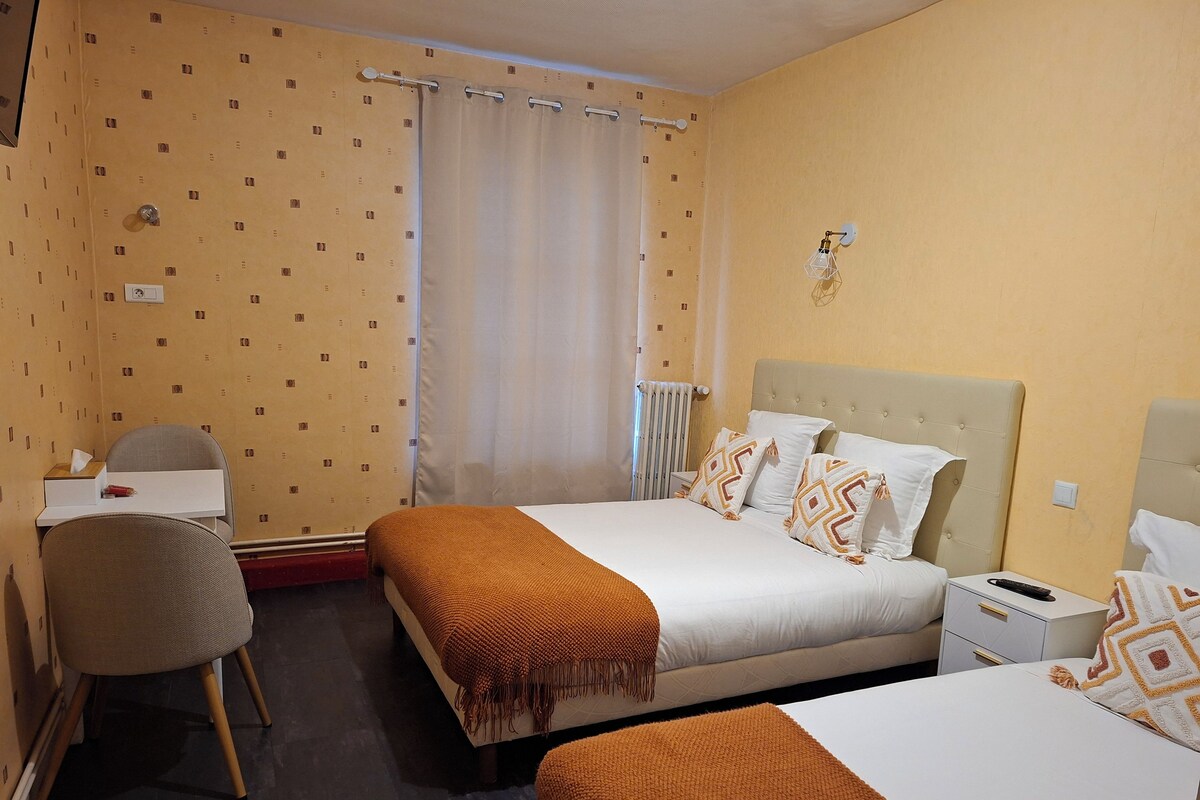 A hotel room with two beds, a desk, and a chair.