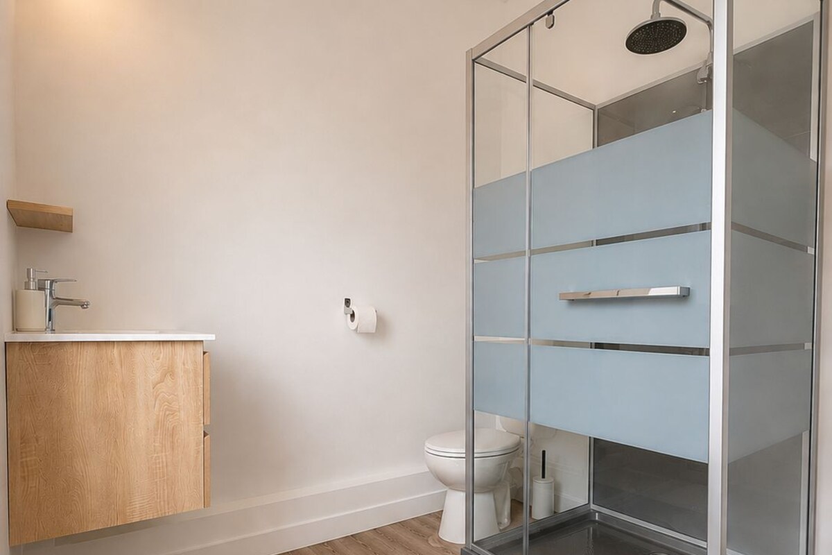 A modern bathroom with a glass shower enclosure, a wooden vanity, and a white toilet.