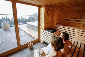 A sauna with wooden benches and a hot tub, large windows, and a view of trees. - Garni & Wellness Anderle (Vignola-Falesina)