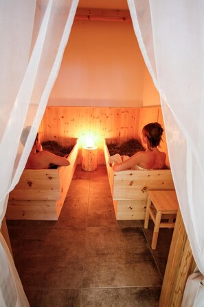 A sauna with two wooden benches and a central heater. - Garni & Wellness Anderle (Vignola-Falesina)