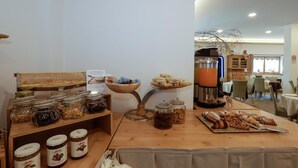 A breakfast buffet with various food items, a coffee machine, and a seating area with tables and chairs. - Garni & Wellness Anderle (Vignola-Falesina)