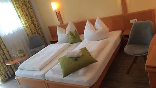 Une chambre d’hôtel avec un lit, deux chaises, une table de chevet et une lampe.