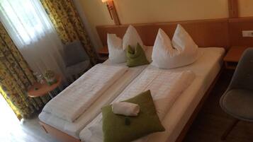 Habitación de hotel con cama doble, dos mesitas de noche, una silla y una lámpara.