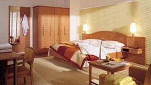 A hotel room with a bed, bedside tables, a desk, and a chair.