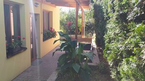 A narrow pathway leading to a building with a yellow facade, wooden shutters on windows, and potted plants along the walls. - Penzion Ubytování Květinová (Krelov)