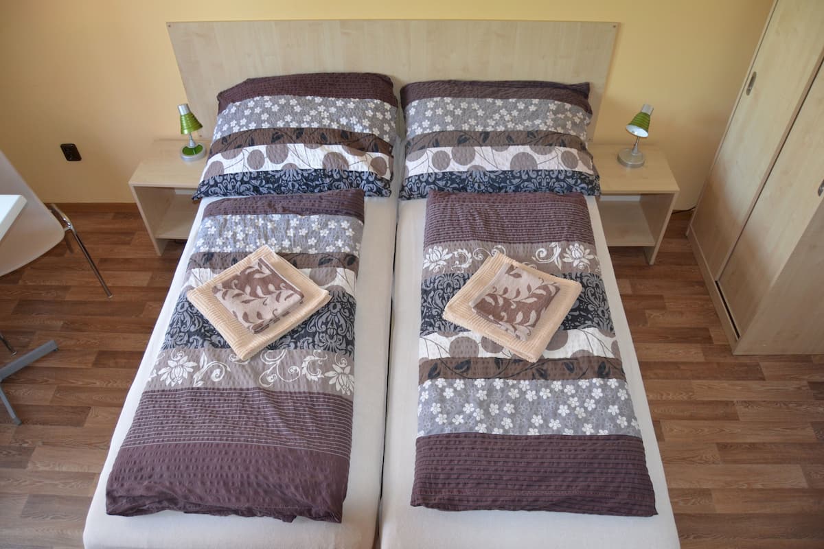 A double bed with patterned bedding and two bedside tables with lamps.