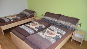 A room with two single beds, each with a wooden frame, a nightstand, and a lamp. - Penzion Ubytování Květinová (Krelov)