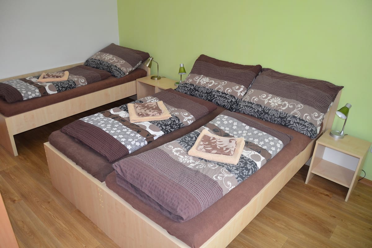 A room with two single beds, each with a wooden frame, a nightstand, and a lamp.