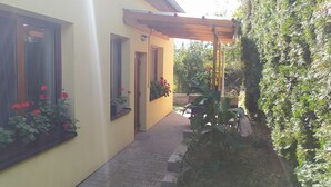 A yellow building with large windows and a covered outdoor area with plants. - Penzion Ubytování Květinová (Krelov)