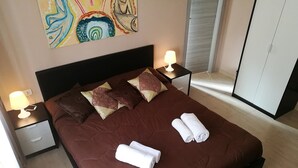 Ein ordentlich bezogenes Bett mit einer braunen Tagesdecke und Kissen, zwei Nachttischlampen und einem Bild an der Wand.