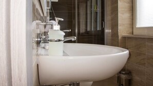 Ein modernes Badezimmer mit einem weißen Waschbecken, chromfarbenen Armaturen und einer Duschkabine aus Glas.