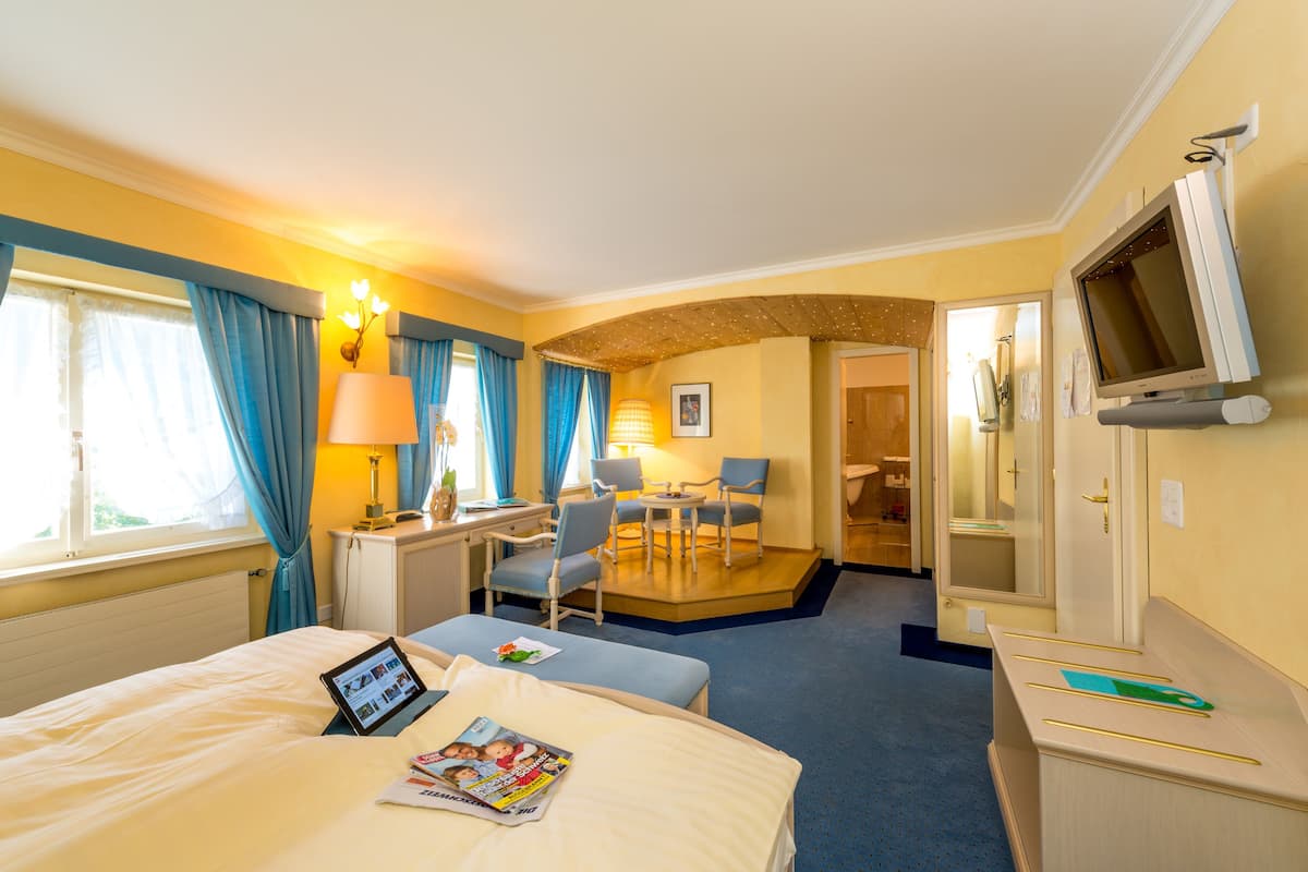 A hotel room with a bed, a desk, a chair, a TV, and a small balcony.