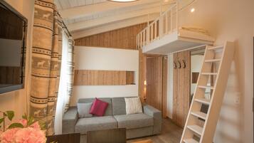A loft-style bedroom with a bunk bed, a wooden ceiling, and a large window.